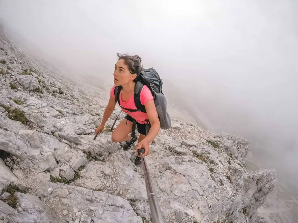 Zoe wearing a pink top trekking up the side of a mountain surrounded by mist despite have hip pain from a labral tear