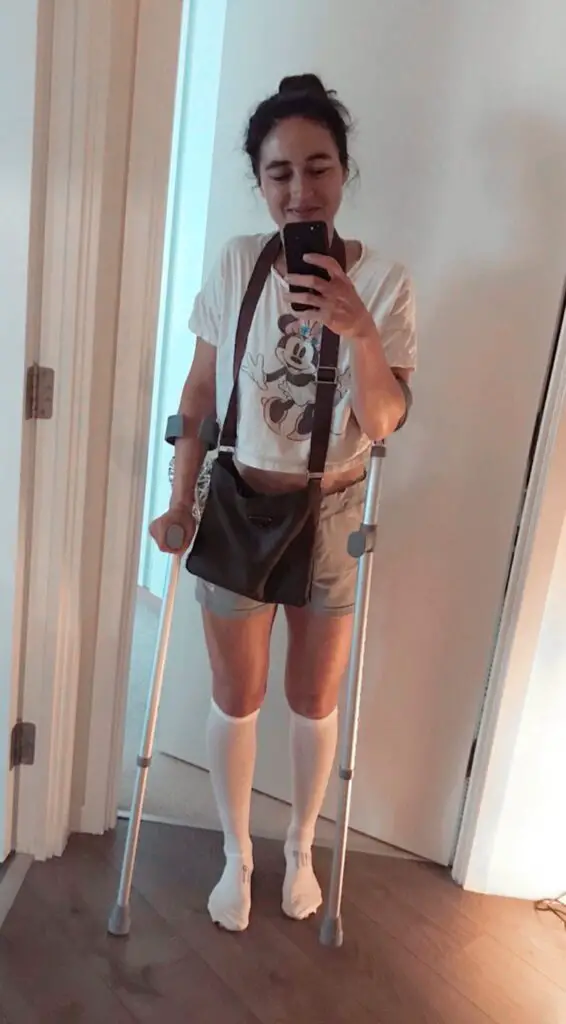 mirror selfie of Zoe with her house back and crutches