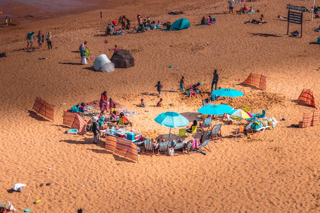 Groups of people on the beach at Broadstairs. There are sun umbrellas and windbreakers dotted about.