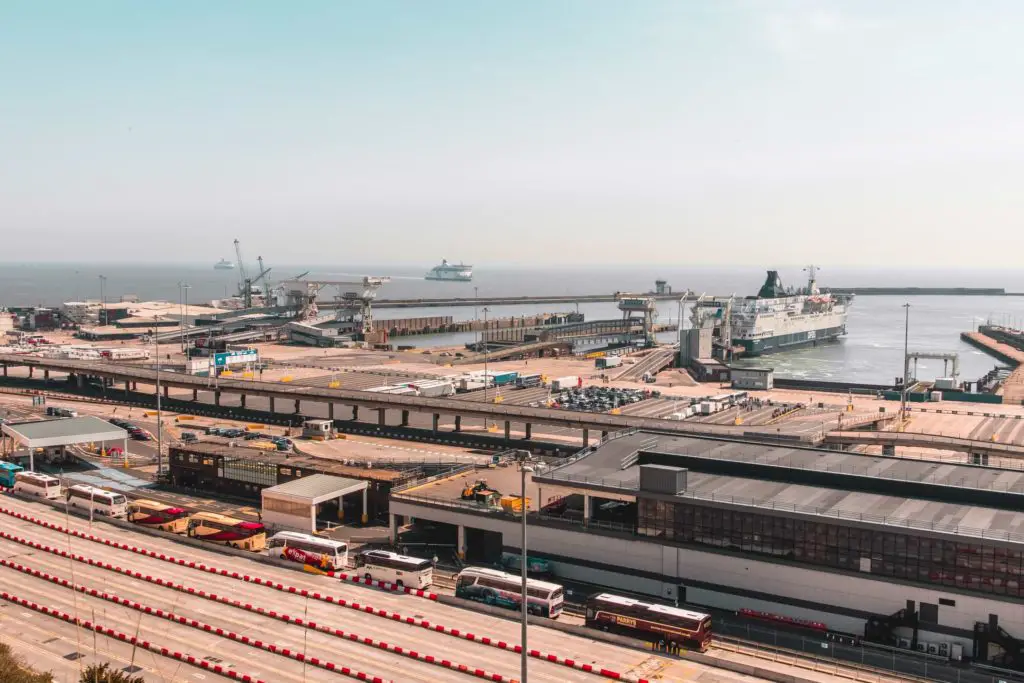 Overlooking the dover ferry port. There is a row of coaches queuing up and a ferry coming into port in the distance.