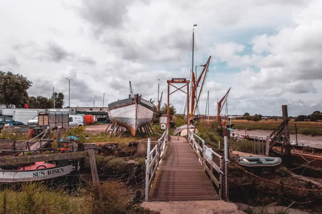 A mini bridge leading to the boat yard with boats on land needing repair. 