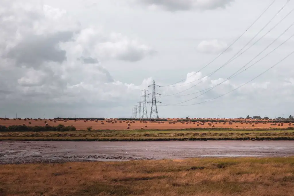 A view of the haystacks in a field with electricity pylons overhead on the Faversham to Whitstable walk. 