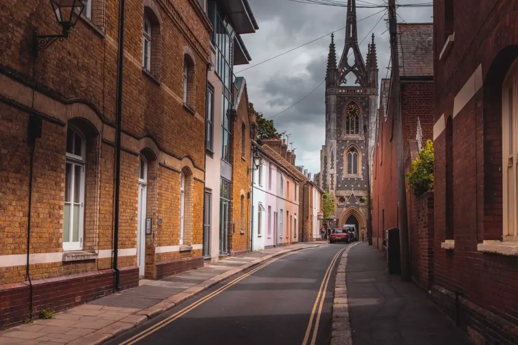A side road lined with old buildings and a church at the end in Faversham.