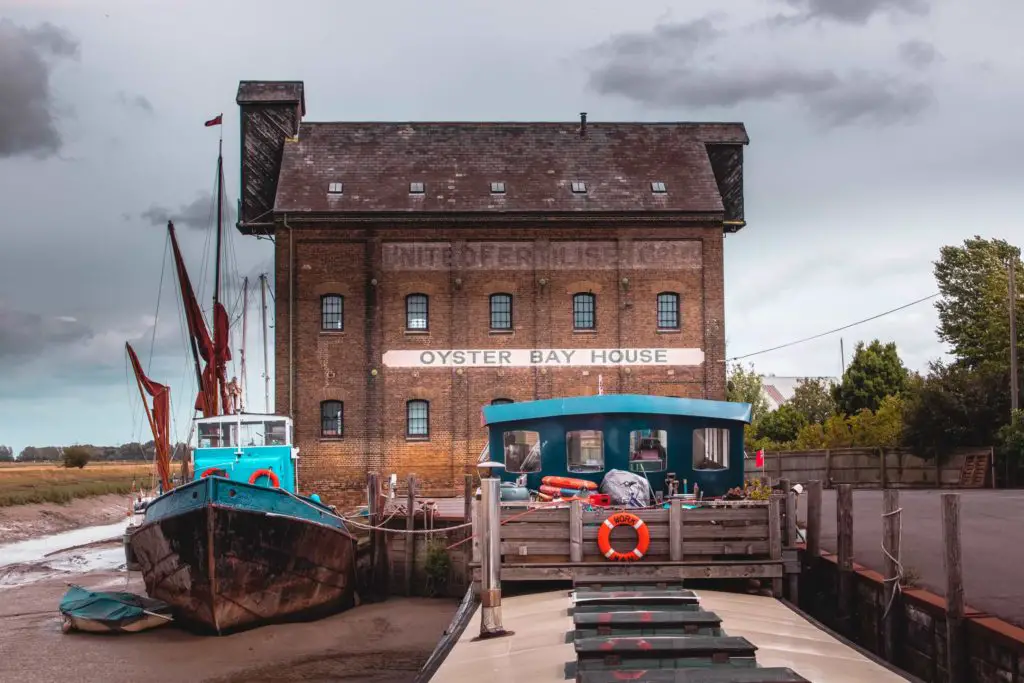 Oyster Bay house, behind a boat and a barge sitting on the sea bed during low tide.