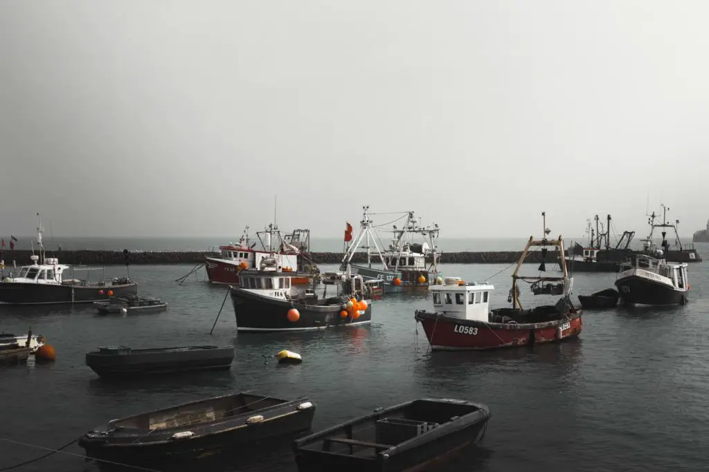 Fishing boats and row boats at Folkestone pier on a misty day..