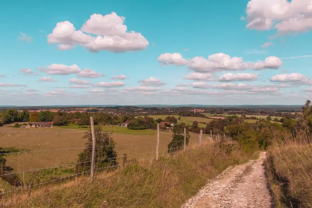 A trail leading downhill, with a view of houses down below on the walk from Hassocks to Lewes and Ditchling Beacon.