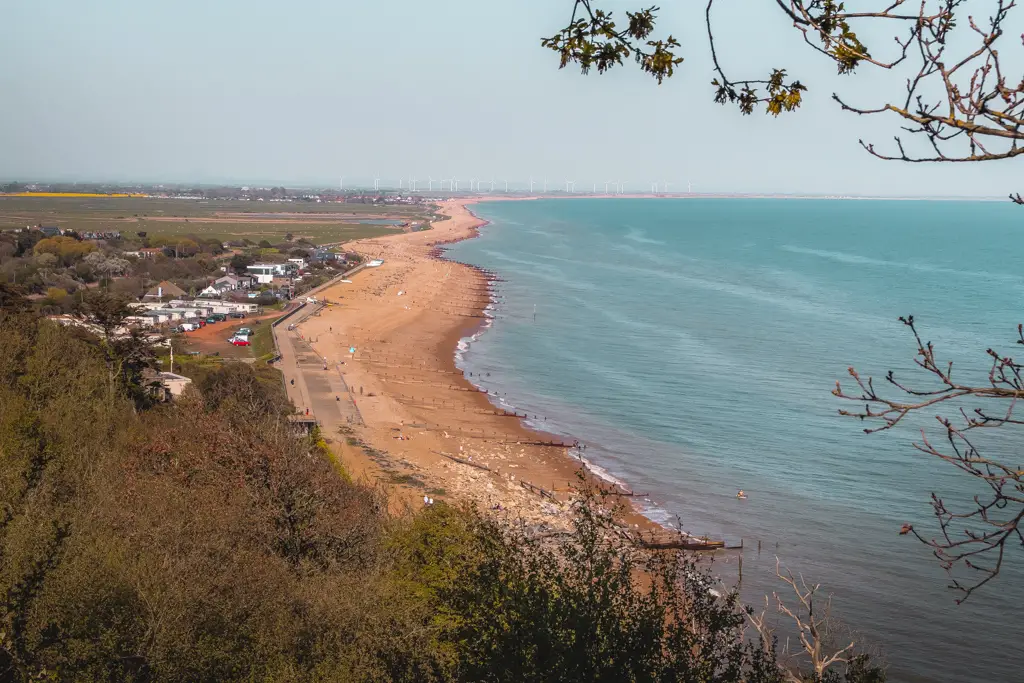 A view looking down at Pett Level beach with wind turbines in the distance on the Hastings to Rye coastal walk.