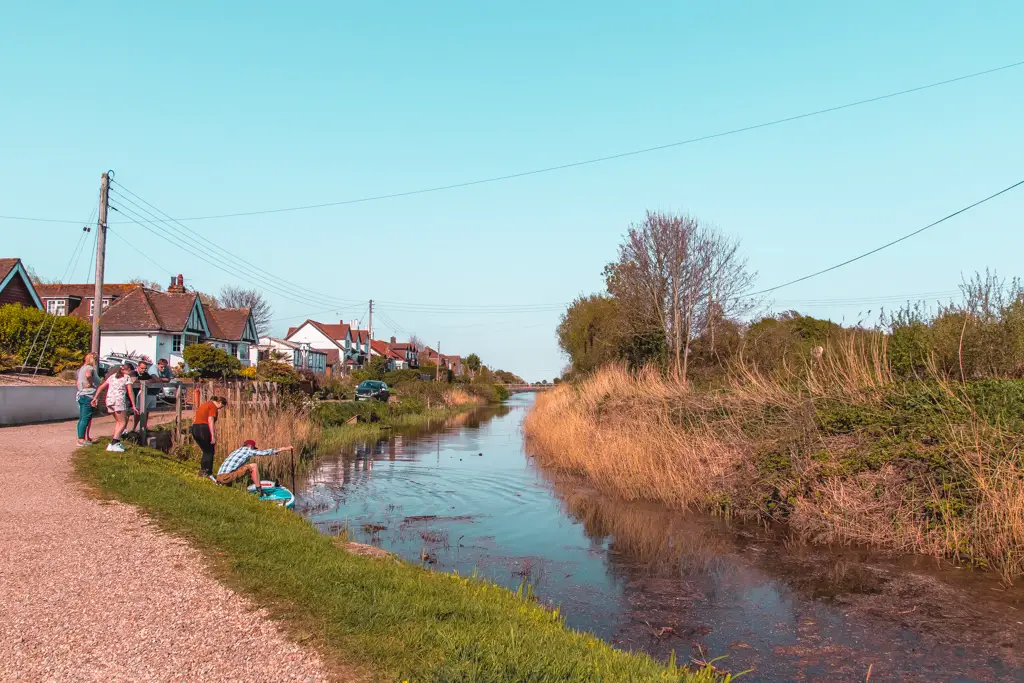 A canal with people playing on the side on the Hastings to Rye walk.