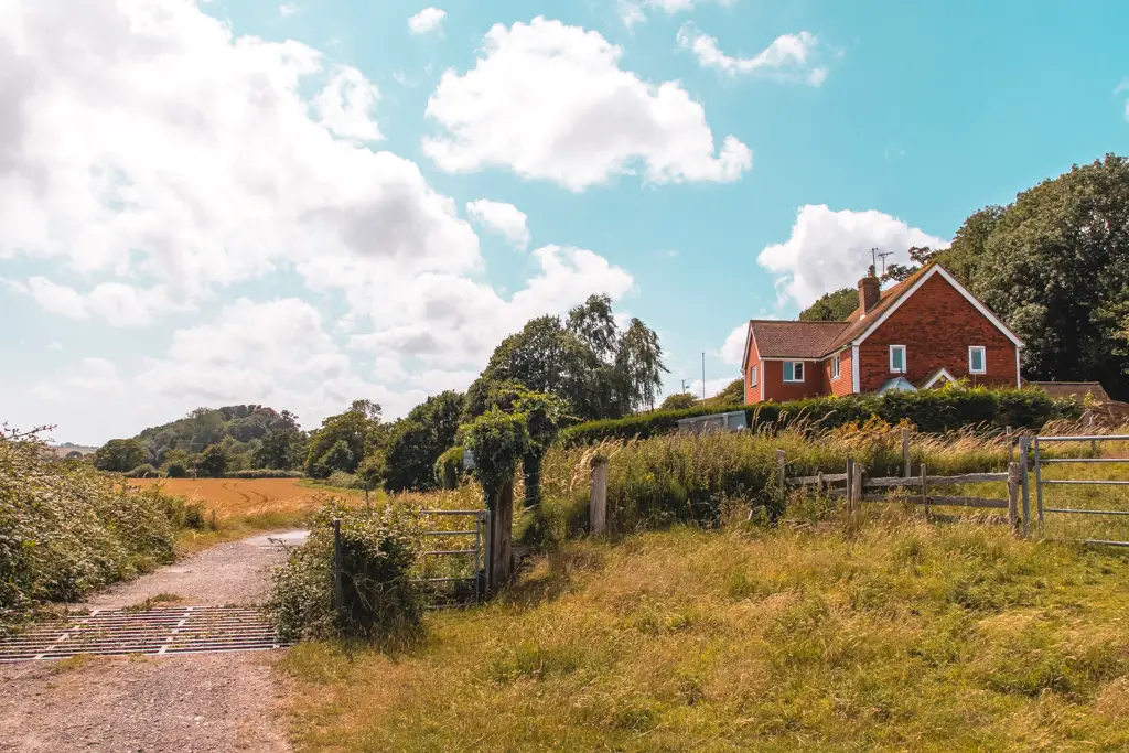 A cute house surrounded by fields and a dirt track marking the route for the Hastings to Rye walk.