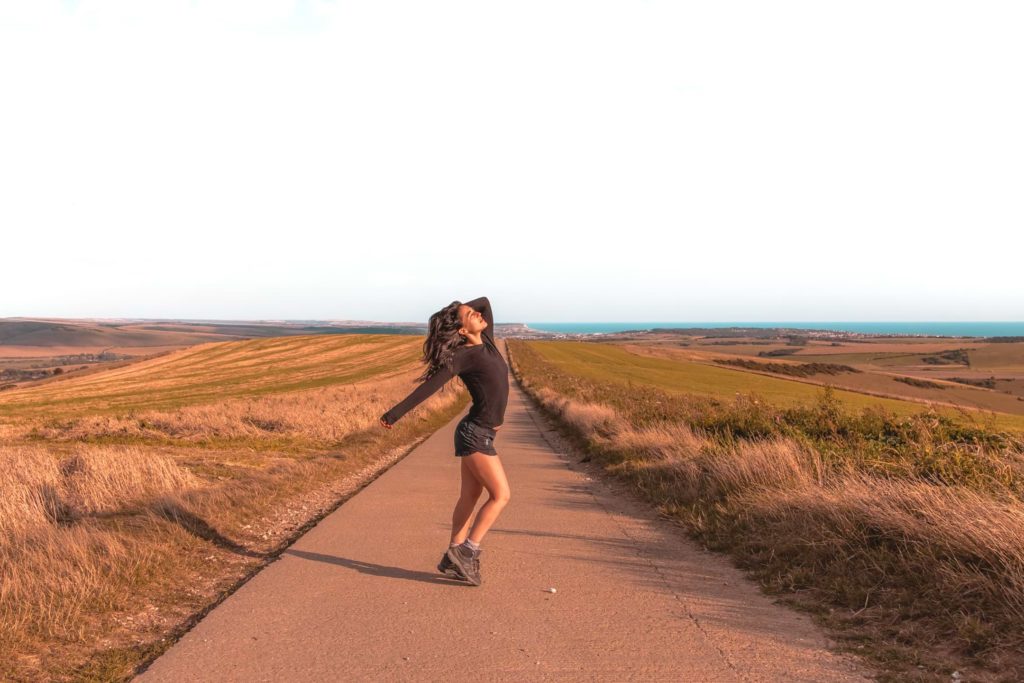 Zoe Tehrani posing on a road on the walk from Lewes to Southease. The road is in the centre of the frame and leads out to the horizon. There are fields either side of the road.