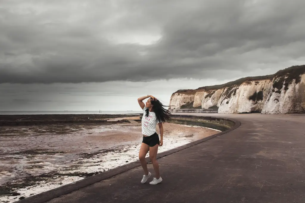 Zoe posing on the promenade on the Margate to ramsgate walk. With wind blown hair on a dark cloudy day.