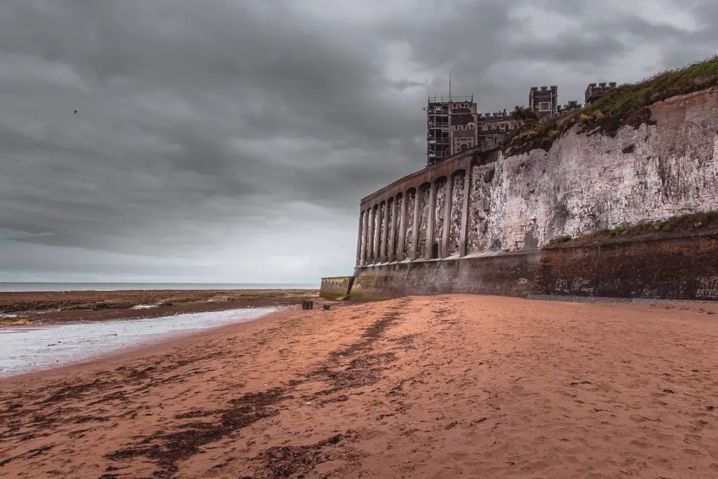 A sandy beach next to the cliff with Kingsgate castle perched on top.