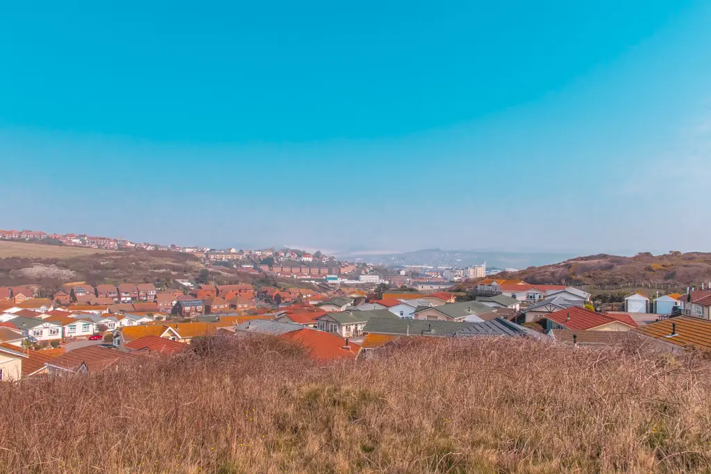 Orange rooftops of Newhaven surrounded by hills. The sky is blue.
