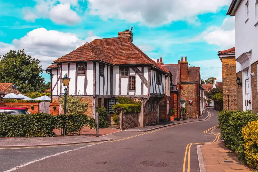 A historic house on a residential street in Sandwich. With a bright blue sky with fluffy white clouds as a backdrop.