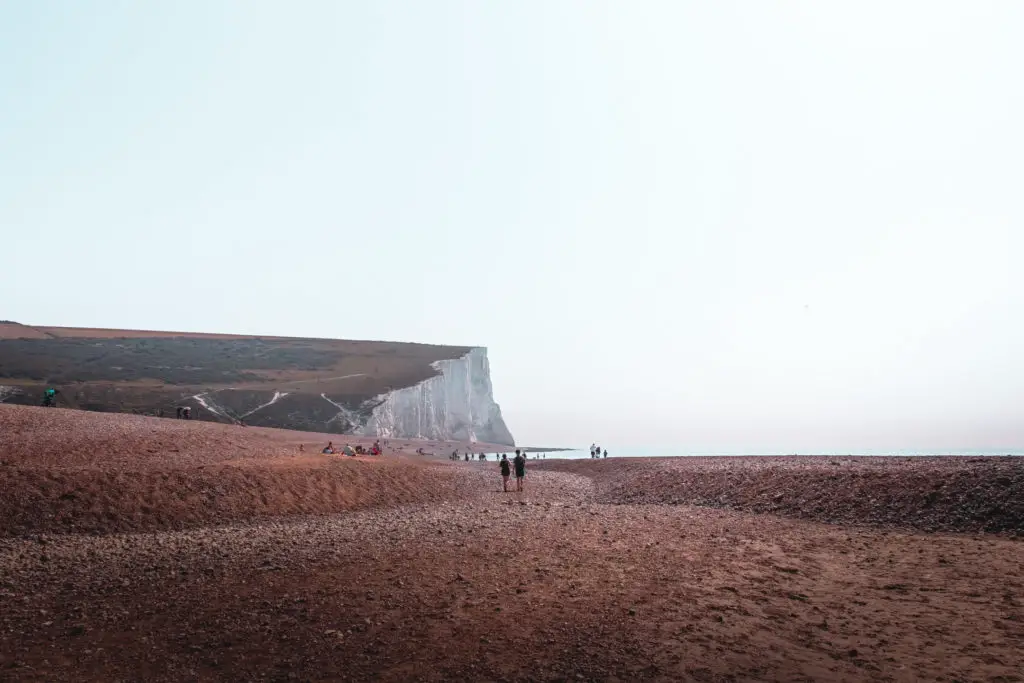 A shingle beach with a white cliff in the distance on the walk from Seaford to Eastbourne.