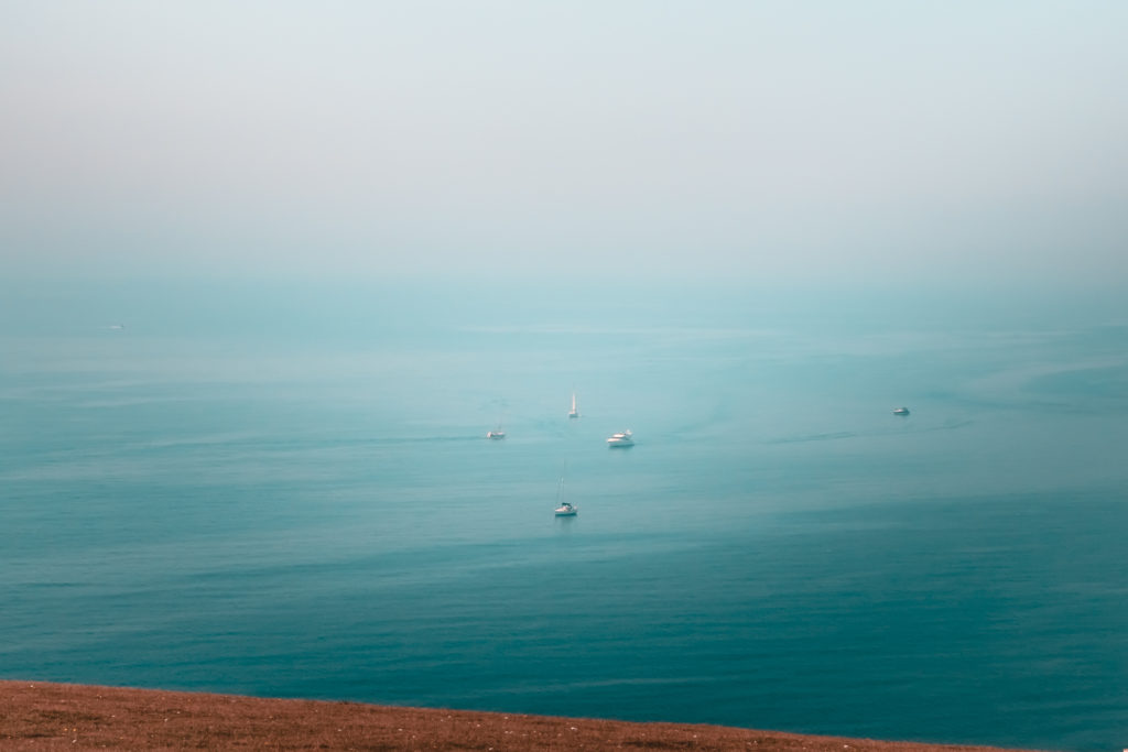 Four boats way in the distance in the sea.