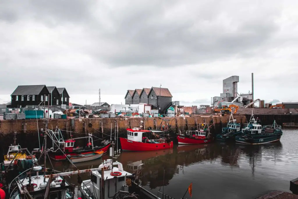 Whitstable Harbour filled with fishing boats. The water is dark, the sky is cloud. 