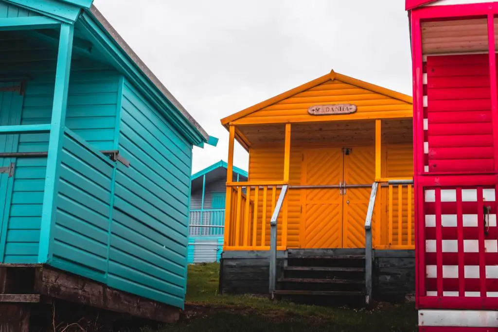 Turquoise, orange and red beach huts close up on the walk near whitstable.
