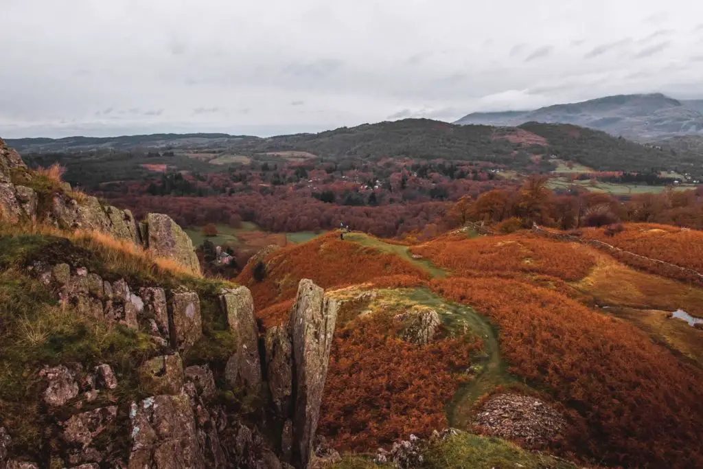 A view looking down at the rolling hills in shades of green and orange from the top of Todd Crag.