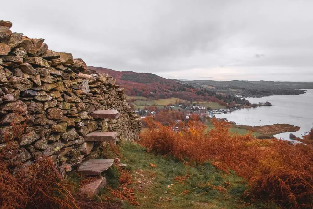 A stone wall on the left with stone steps sticking out of it along the Todd Crag walk.