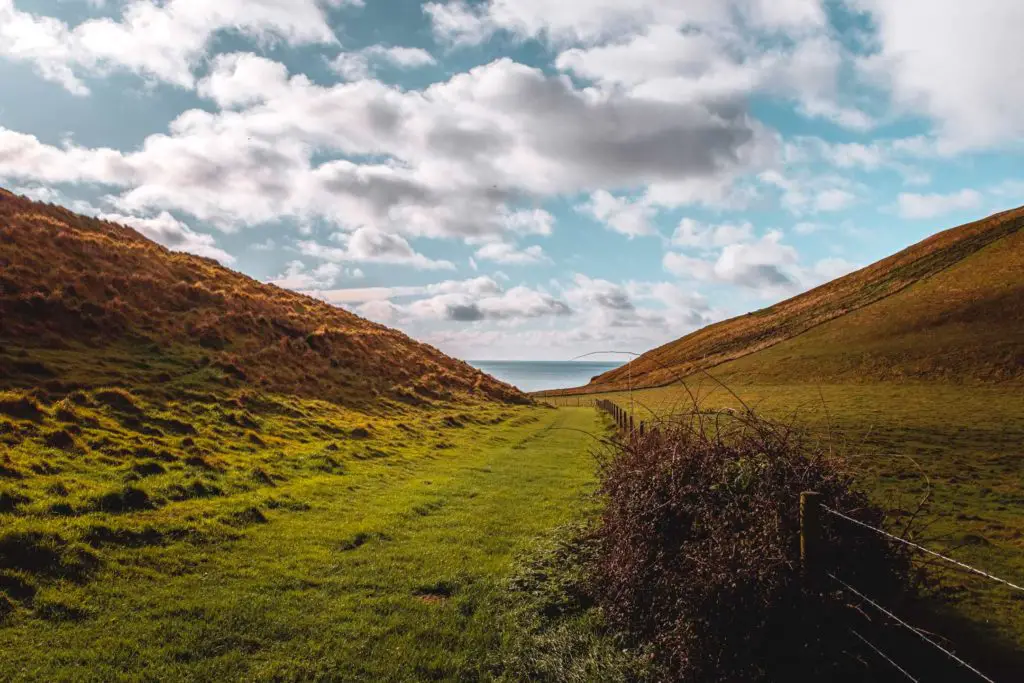 Looking through the grassy valley with a glimpse of the sea at the end.