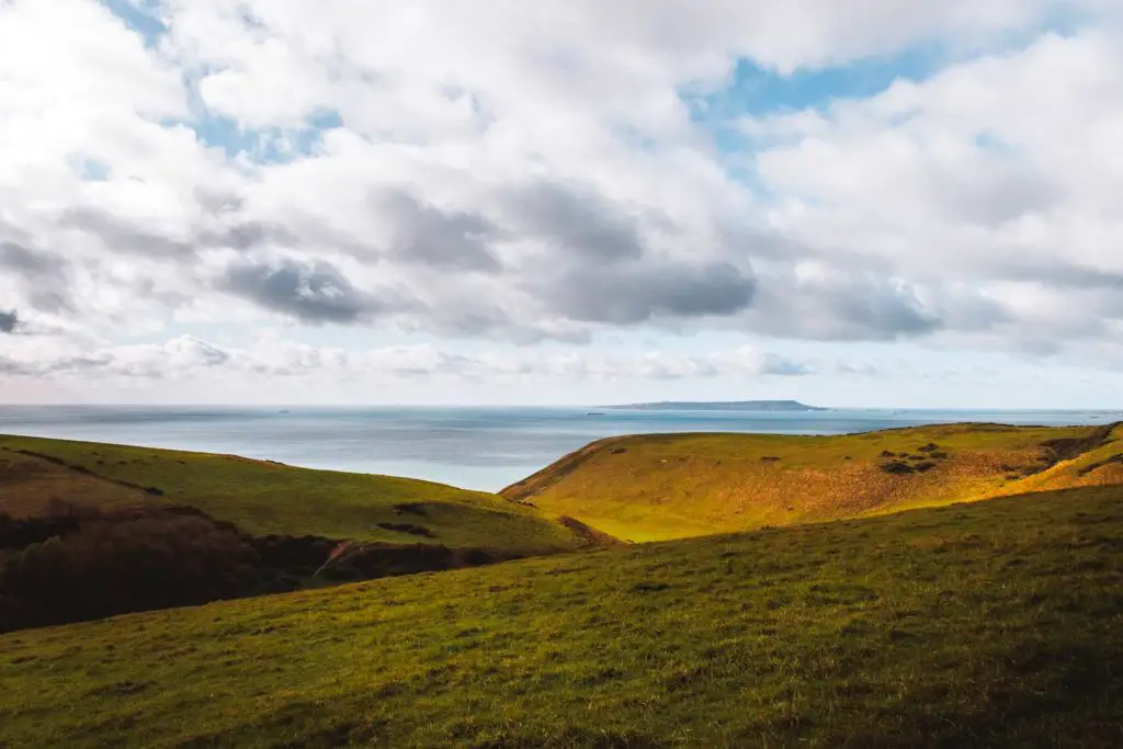 Rolling green hills with the sea as a backdrop of the walks from Lulworth Cove to Durdle Door.