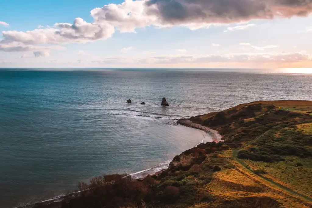 A view of the coastline of the Jurassic coast with a few rock formations jutting out of the water.