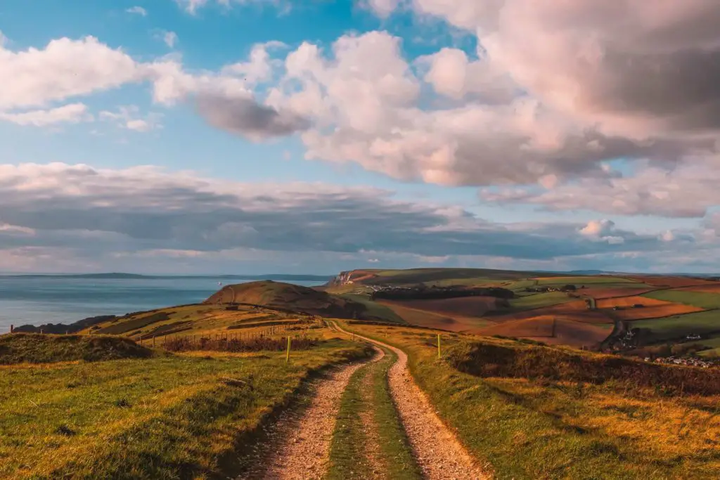 A winding gravel trail on the Lulworth Cove hike, leading to the rolling hills in shades of green and orange.