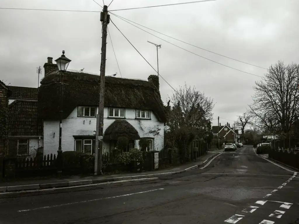 A white house with a thatched roof in Brockenhurst village.