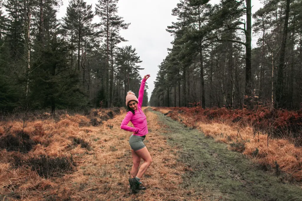 Zoe Tehrani posing on a grass trail on the walk from Ashurst to Lyndhurst. She is wearing a pink top and grey shorts and a light pink hat.
