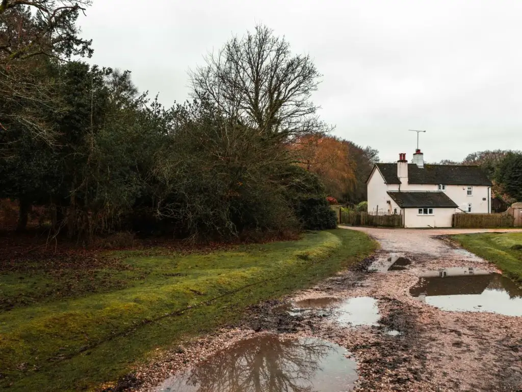 A dirt trail with a white house at the other end on the Brockenhurst village walk.