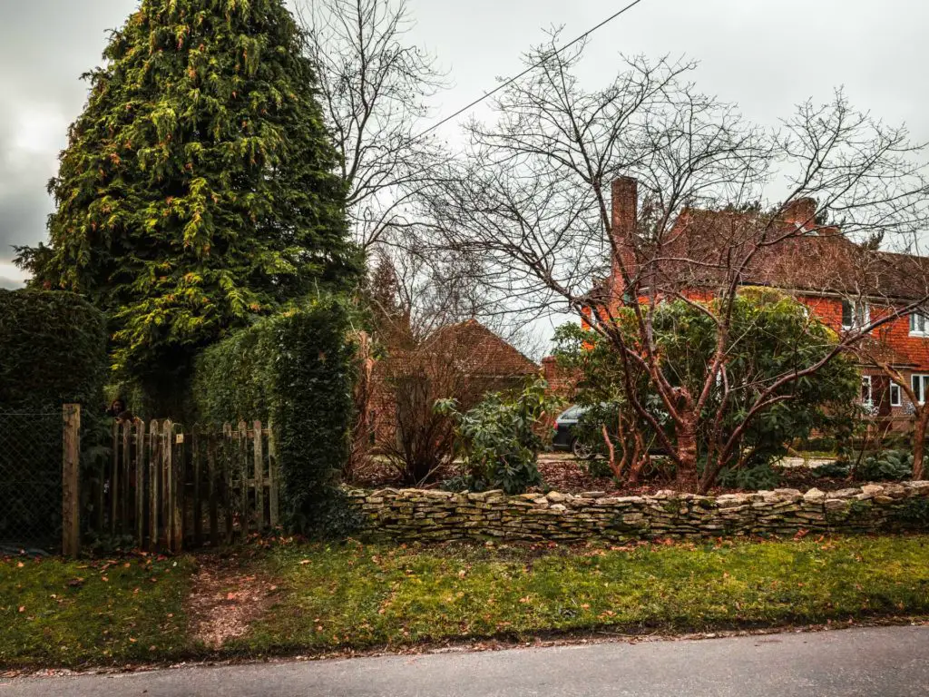 A gate across the road leading to a the trail for the Brockenhurst to Lymington walk. There are houses to the right of it.