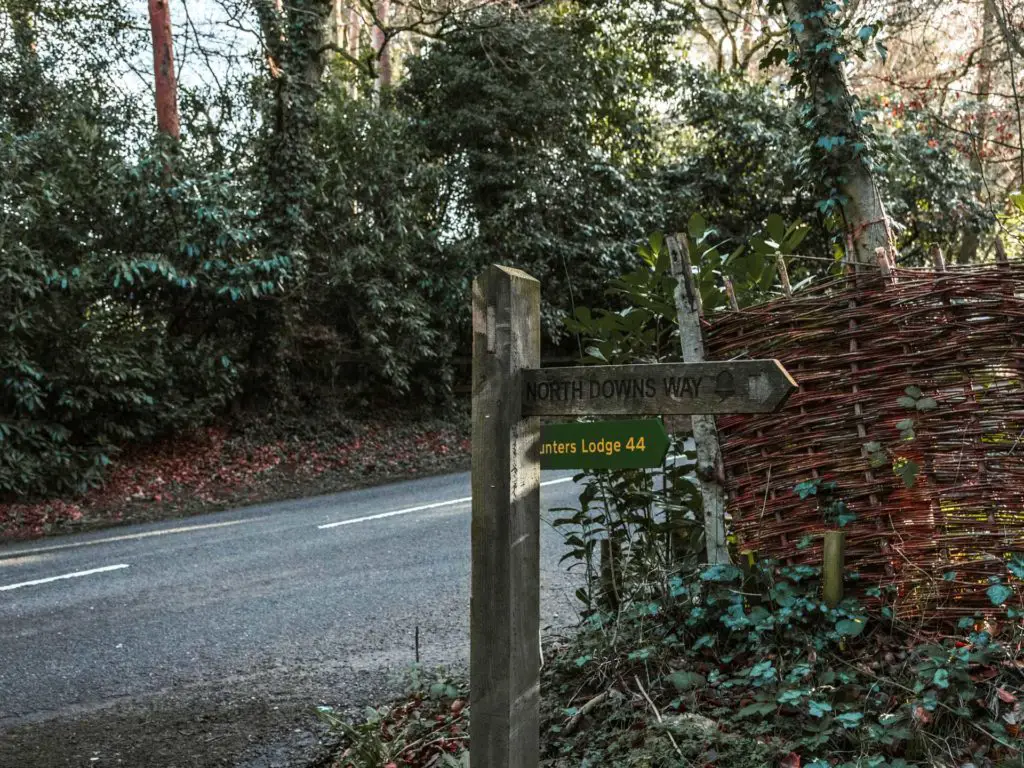 North Downs Way signpost next to a road junction.