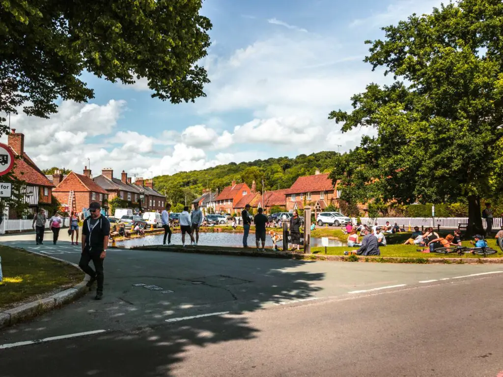 The duck pond in Aldbury surrounded by crowds of people.