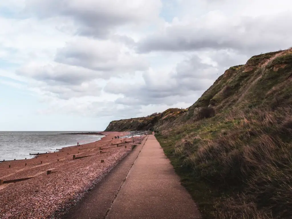 A long straight path with grassy cliffs on the right and shingle and sea to the left along the walk from Herne Bay to Margate.