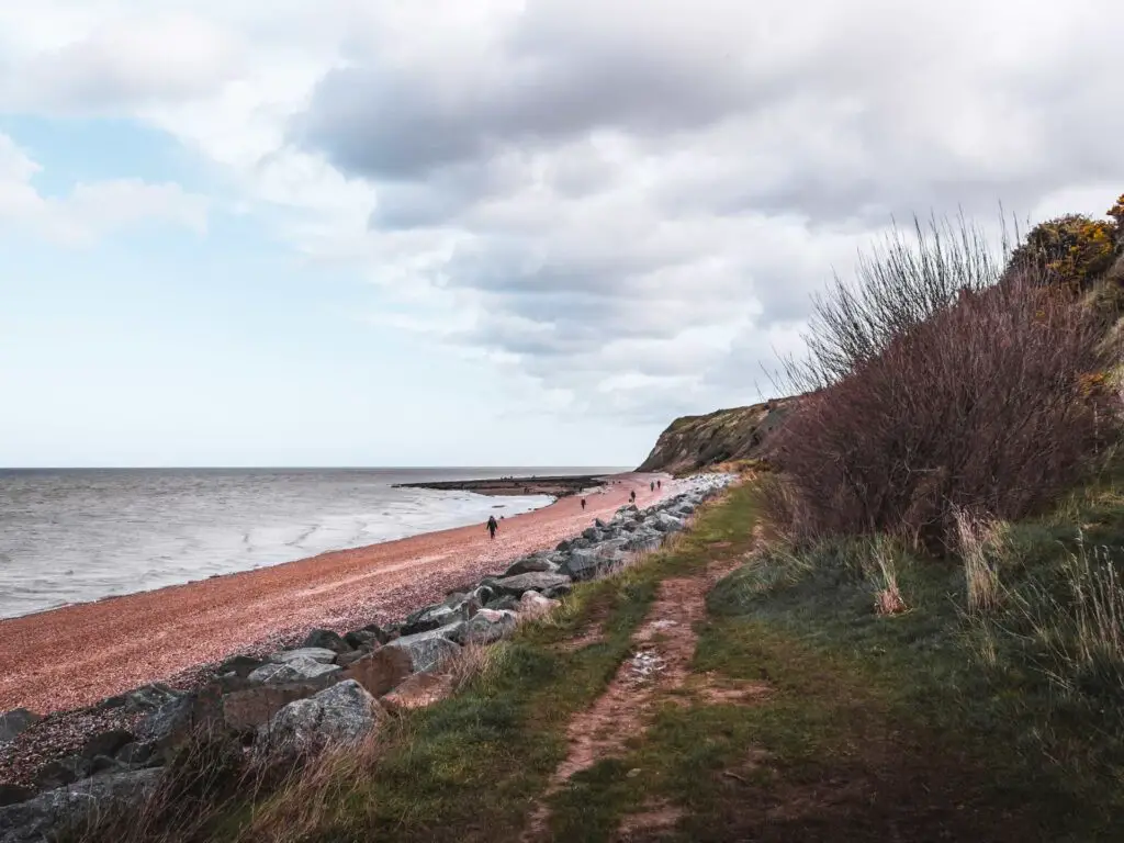 A dirt path with grassy cliffs on the right and the shingle beach on the left along the walk from Herne Bay to Margate.