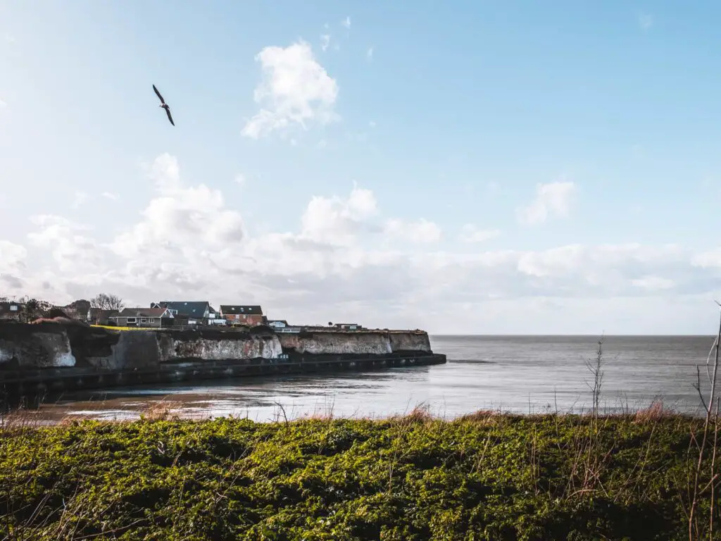 The sea with a village on top of the cliffs in the distance along the walk from Herne Bay to Margate via Reculver.