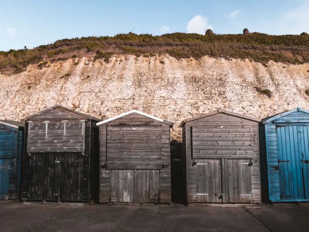 Wooden shabby beach hits in black and blue, standing in front of white cliffs at Westgate on Sea.