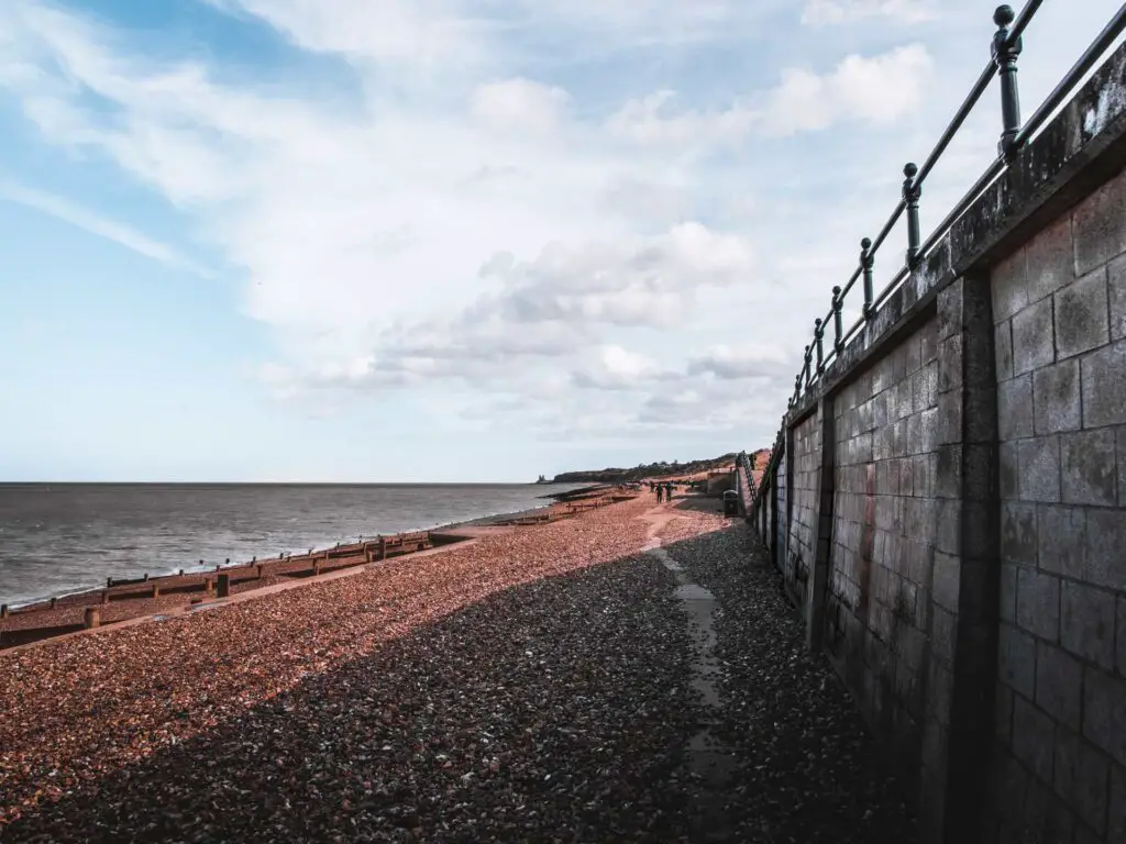 A very slim path surrounded by shingle and the sea wall to the left.