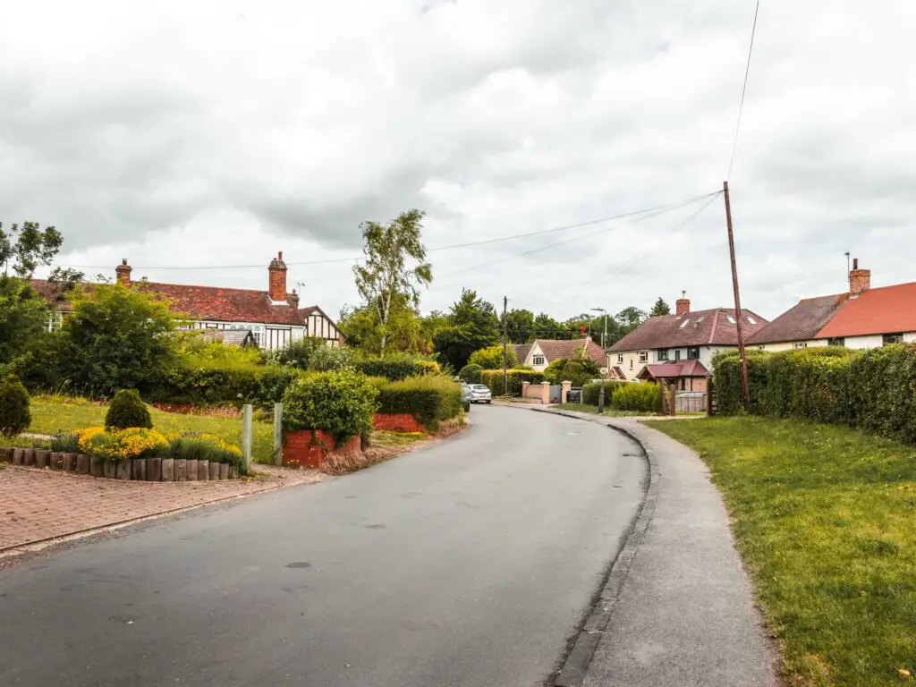 A residential street, with the road curving around to the left. There are small houses along the side of the road.