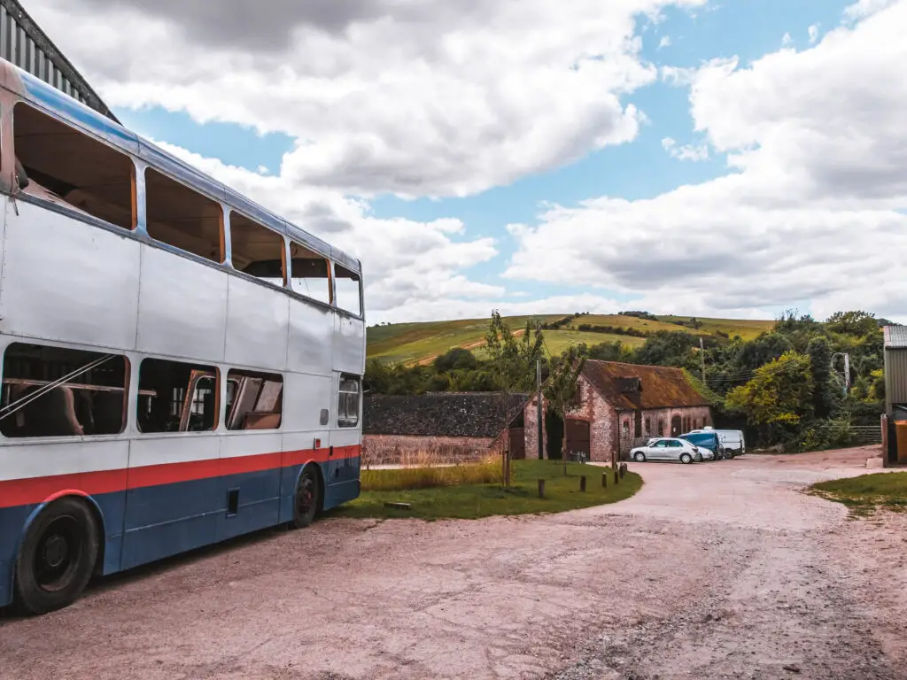 An abandoned bus with a farmhouse ahead.