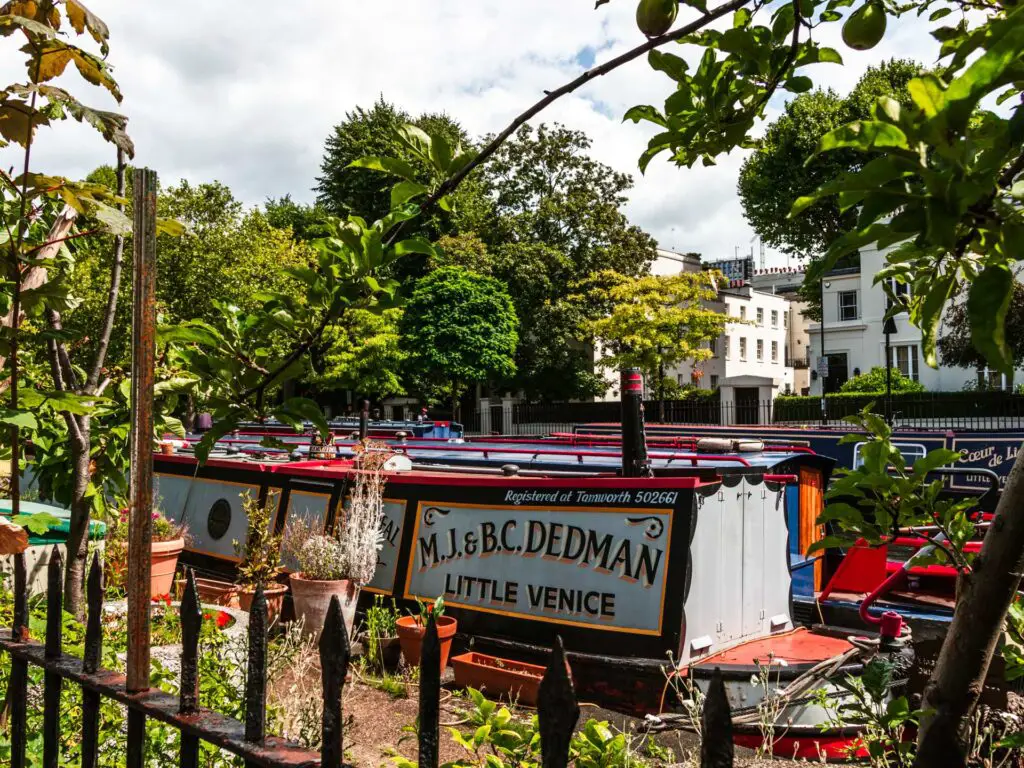 A canal boat on the other side of a black fence.