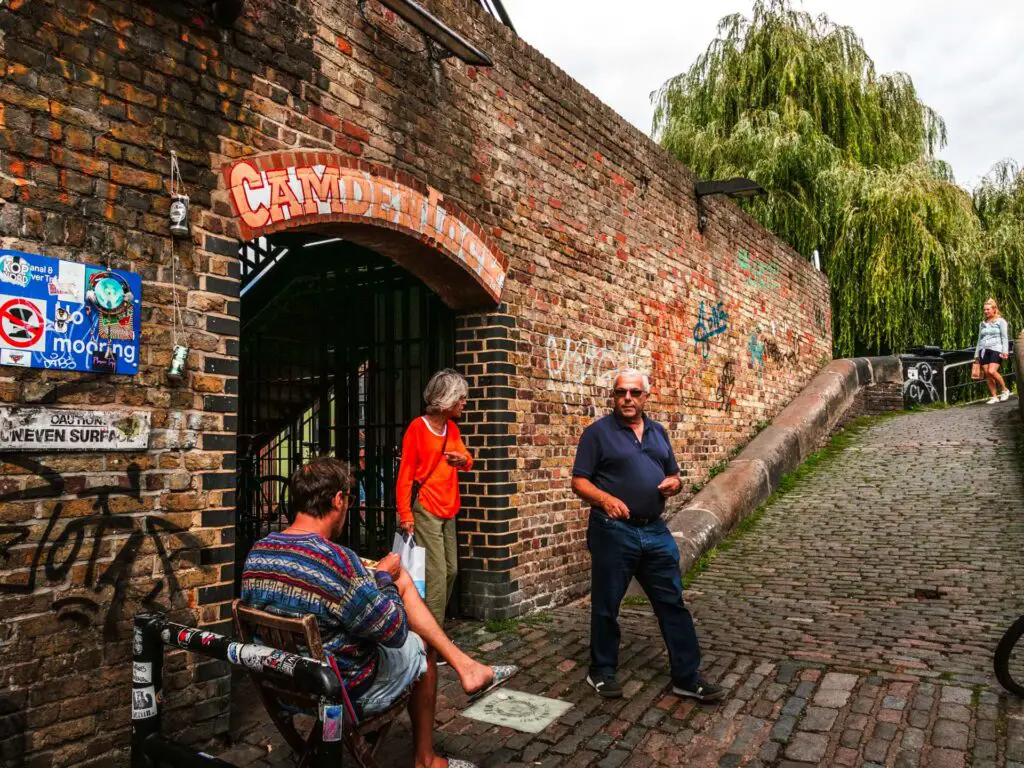 A brick wall with an archway entrance to Camden Lock. 