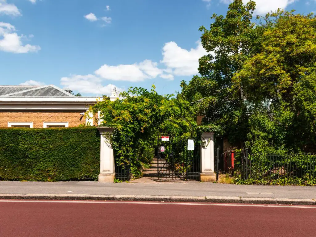 The red road with the entrance gate to St Johns Lodge on the other side.