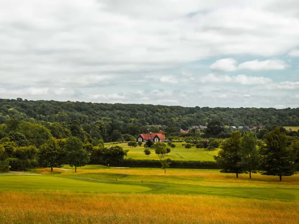 A golf course in the Chilterns at the end of the circular walk from Tring to Ivinghoe Beacon. There is woodland on the other side and a house with a red roof.