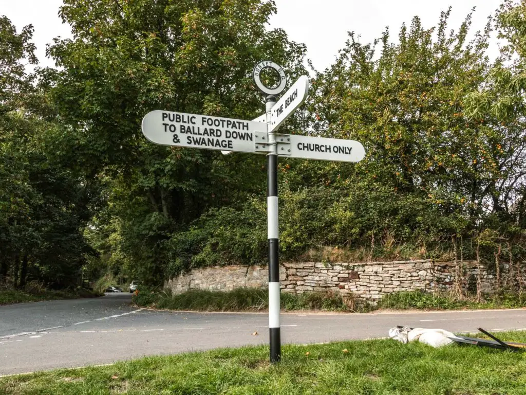 Black and white signage pointing in three directions to Swanage, the beach and a church.