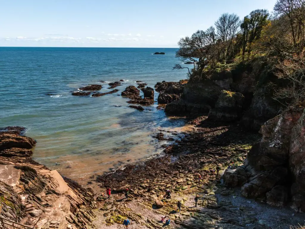 A rocky beach cove surrounded by cliffs on the Dartmouth castle walk. The sea is blue.