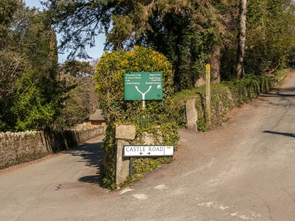 A road as it splits in two. The road sign says Castle road.There is lots of greenery lining the roads.