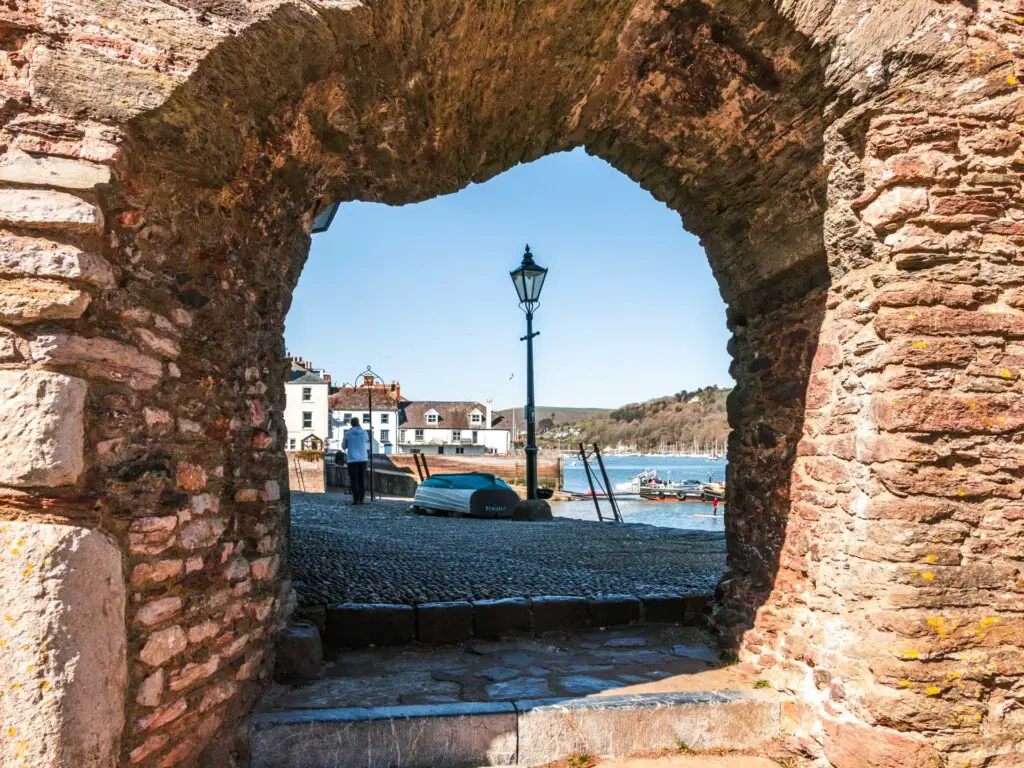 Looking through the brick window onto a cobble path with the river behind it and dome buildings far away.