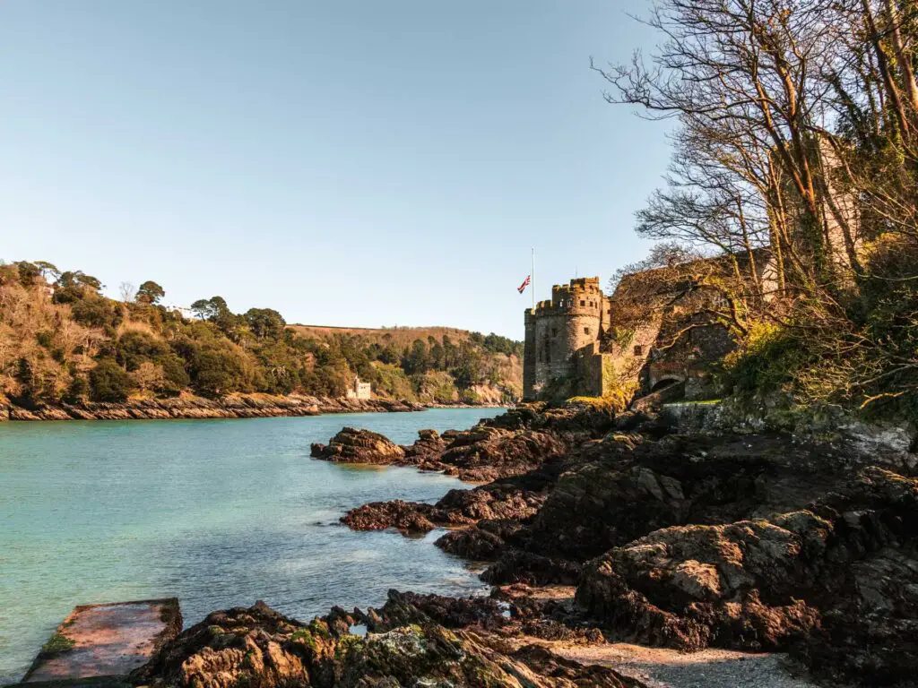 Dartmouth Castle on the other side of black rocks on the River Dart. 